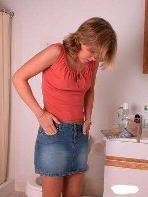 Amateur girl Karen hikes her denim skirt in the bathroom to expose her panties on adultfans.net