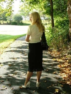 Clothed blonde Iona shows off her white stilettos in a long skirt by a park on adultfans.net