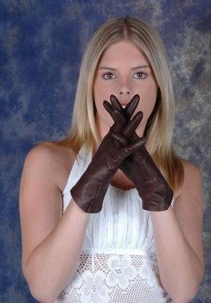 Blonde female pulls on brown leather gloves while wearing a white dress on adultfans.net