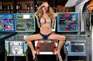 Inked chick Sarah Jessie toys her pussy atop a pinball machine while alone on adultfans.net