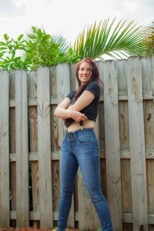 Hot redhead Andy Adams loses her t-shirt & jeans in the yard to pose naked on adultfans.net