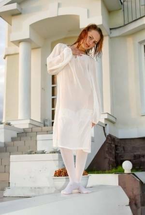 Barely legal redhead Alisabelle poses nude in white stockings outside a house on adultfans.net