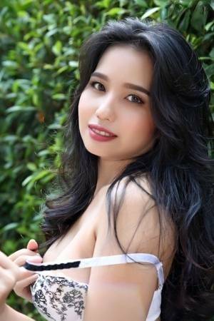 Beautiful Asian girl Norah gets totally naked next to a hedge in a garden on adultfans.net