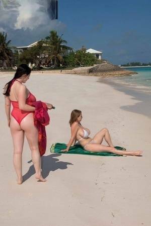 Busty lesbian girls let their huge knockers loose to kiss & lick on the beach on adultfans.net