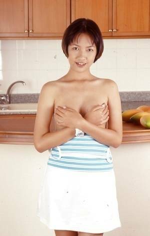 Clothed Asian with tiny tits is posing in the kitchen with spread legs on adultfans.net