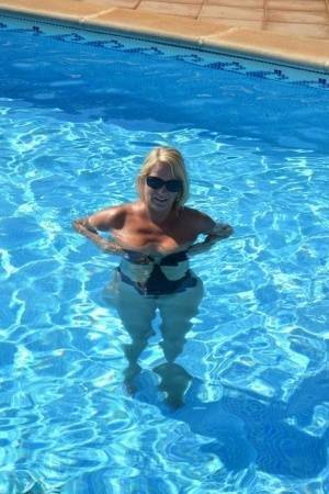 Middle-aged blonde Sweet Susi frees her tits & pussy from a swimsuit by a pool on adultfans.net