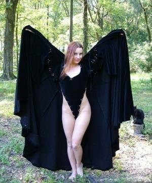 Redhead amateur Amber Lily models nude in a forest draped in a black cape on adultfans.net
