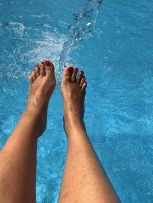 Mature woman Sweet Susi dips her painted toenails into a swimming pool on adultfans.net