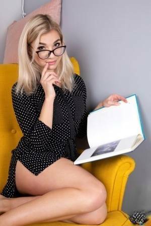 Geeky blonde Amelia undresses on a chair before playing with her shaved pussy on adultfans.net