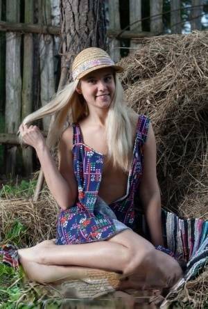 Young blonde Agnes H doffs a dress to get naked on weathered straw in a yard on adultfans.net