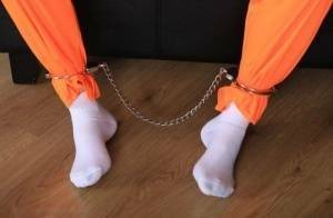 Female prisoner is left alone while cuffed in an orange jumper and white socks on adultfans.net