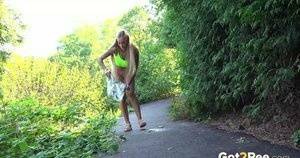 Blonde teen Daisy Lee takes a piss on a paved path through the woods on adultfans.net