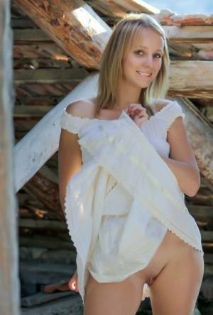 Young blonde Ilona D gets naked in a rustic setting with her boots on on adultfans.net