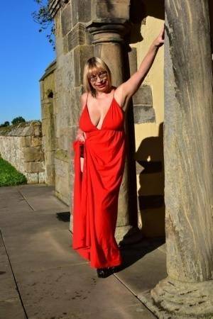 Older blonde Barby Slut doffs a red evening gown to pose nude in hosiery on adultfans.net