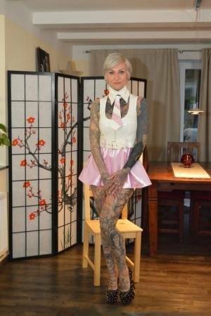 Tattooed platinum blonde Miss Francine models a raincoat over a latex dress on adultfans.net