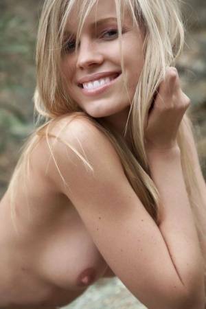 Smiling MILF Marketa shows off her nude body atop a rock outdoors on adultfans.net
