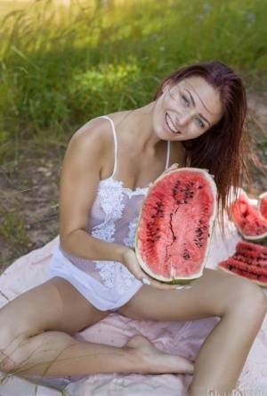 Sweet young girl gets naked while eating a watermelon under a tree on adultfans.net