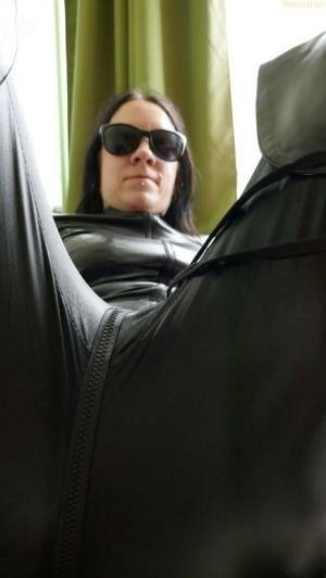 Dark haired amateur models a leather catsuit while wearing dark sunglasses on adultfans.net