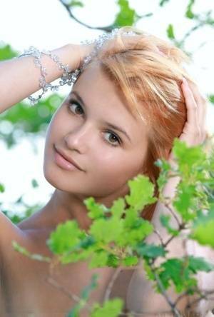 Adorable redhead Violla A displays her naked teen body atop a rock outdoors on adultfans.net