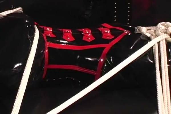 Black and red latex bondage session with restraints and rope harness on adultfans.net