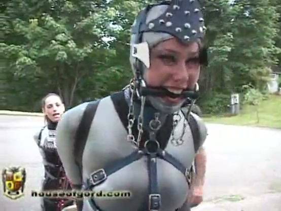 Latex-clad submissive trained with a red cart in outdoor bondage session on adultfans.net