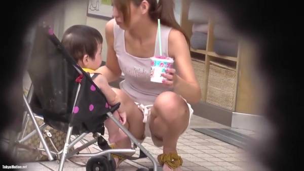 Young mom caught in white tank top as she bends over near her stroller on adultfans.net