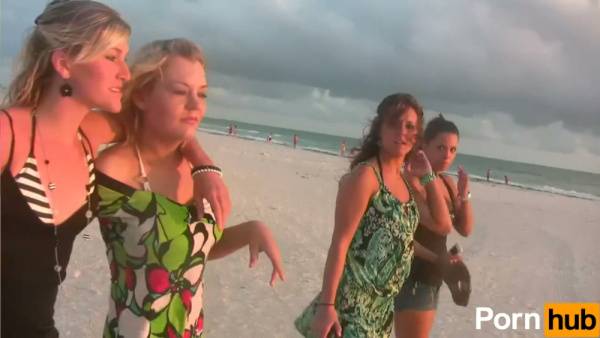 Two tan brunette women playfully expose themselves on a quiet beach on adultfans.net