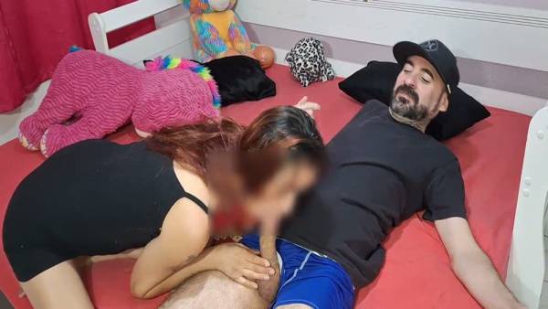 Young woman kneels on red bed as bearded man grips her hips for cumshot on adultfans.net
