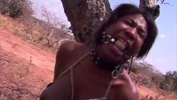 Dark-skinned woman submits to discipline in a leather harness during outdoor training session on adultfans.net