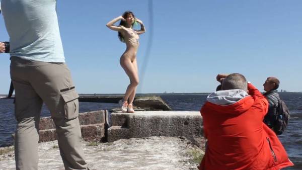 Woman poses nude on a weathered concrete pier during an outdoor photo session on adultfans.net