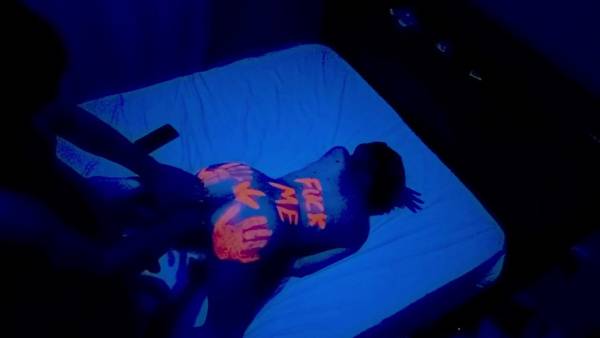 Latina couple glows under blue light with neon handprints during intimate night filming on adultfans.net