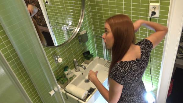 Blonde woman adjusts her hair in front of the bathroom mirror wearing a black floral dress - Usa on adultfans.net