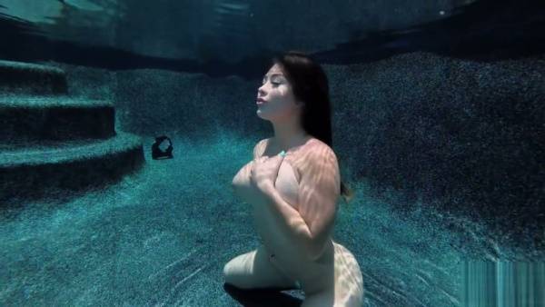 Serena floats submerged in a pool, nude with sunglasses and a tattoo on adultfans.net