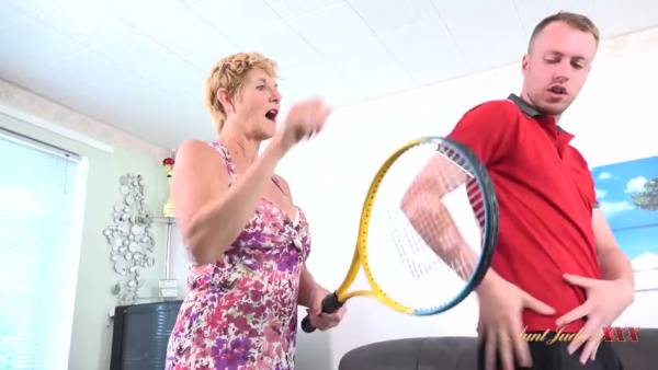 Amateur encounter between a blonde housewife and her young tennis instructor escalates in the living room on adultfans.net