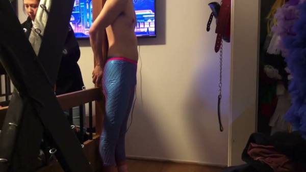 Feminized man bound to bed frame by dominant woman in intimate bedroom session on adultfans.net