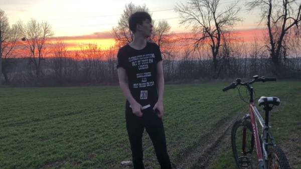 Young man with curly brown hair jerks off outdoors on a red bicycle during sunset on adultfans.net