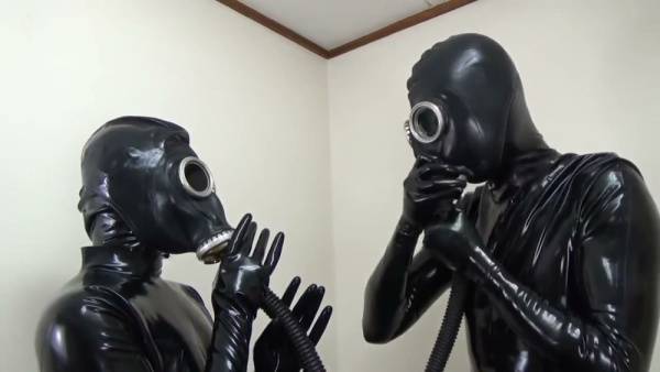 Latex-clad couple explores breathplay with gas masks in a stark white room on adultfans.net